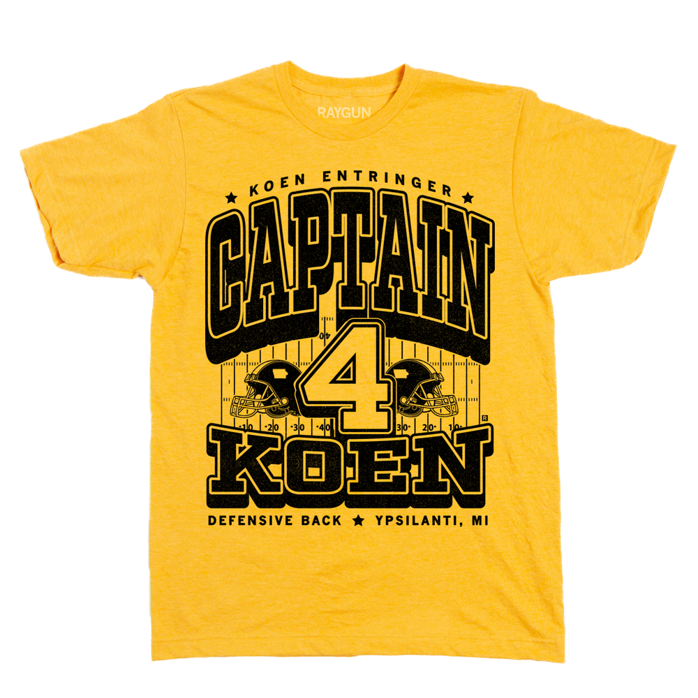 Black ink on a yellow shirt that reads "Koen Entrigner. Captain Koen. Defensive Back. Ypsilanti, MI" over an illustration of a football field with a large number 4 in the center and a football helmet to either side.