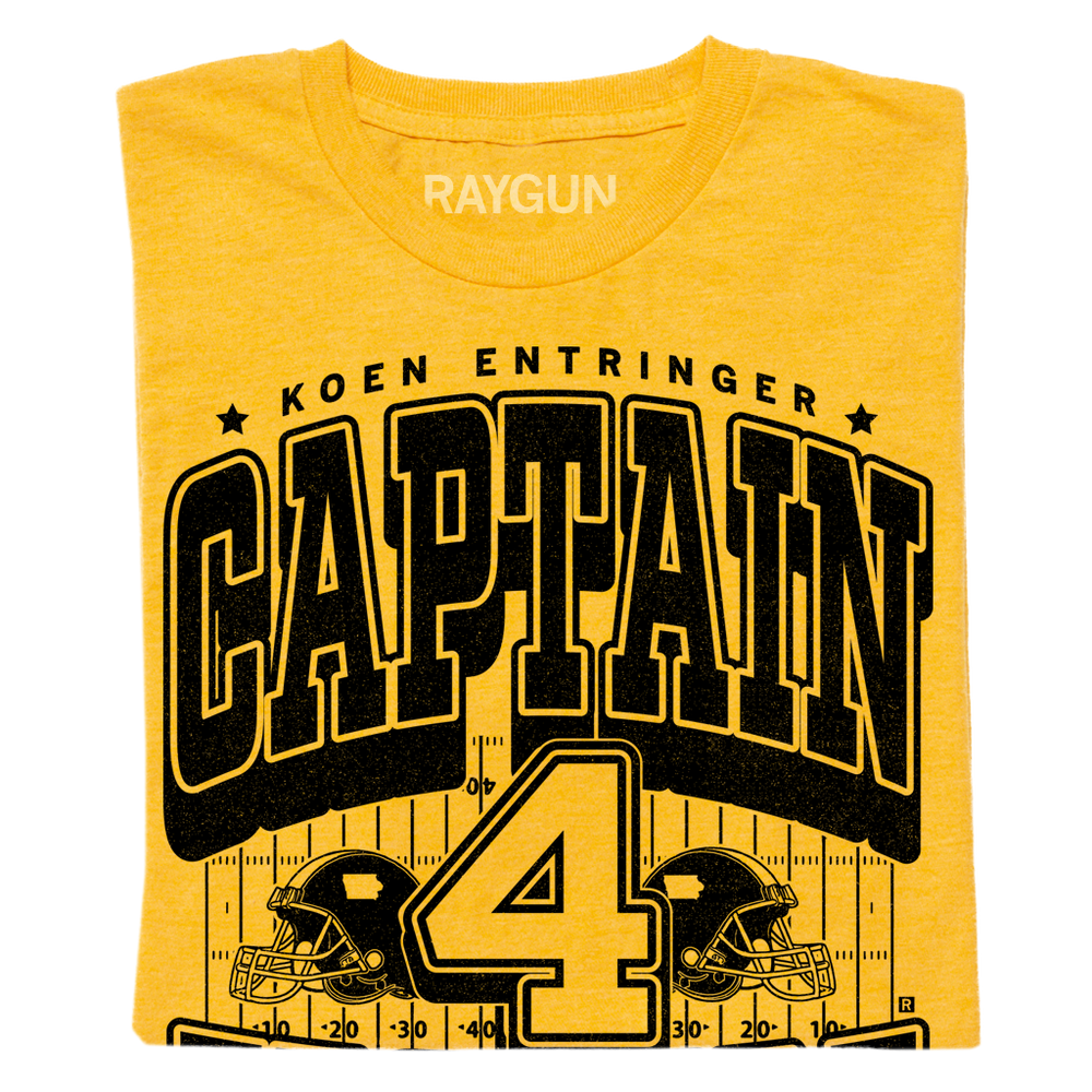 Gold shirt with black ink that reads "Koen Entrigner. Captain Koen. Defensive Back. Ypsilanti, MI" over an illustration of a football field with a large number 4 in the center and a football helmet to either side.