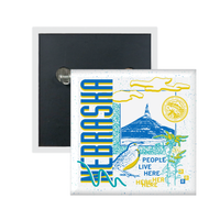 A white square metal button in a retro 90's style with a blue print image Chimney Rock in Nebraska. Sideways vertical text to the left says, "NEBRASKA" with smaller blue and yellow font to the bottom right that reads "People Live Here." There's also yellow flowers, a white bird, teal squiggles, and other colorful accent touches.