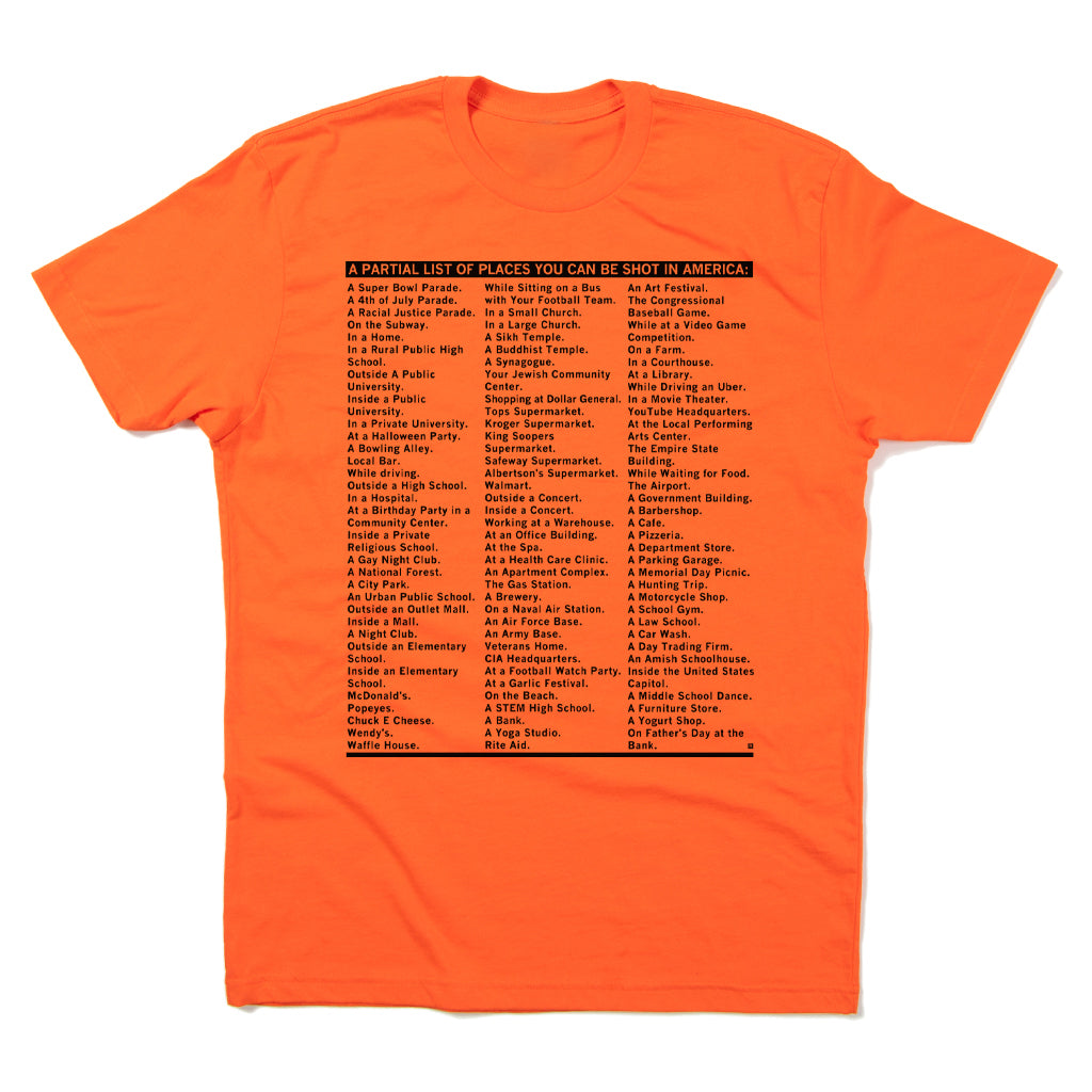 An orange union-printed RAYGUN T-shirt featuring a list of places titled A PARTIAL LIST OF PLACES YOU CAN BE SOUTH IN AMERICA: followed by numerous locations.