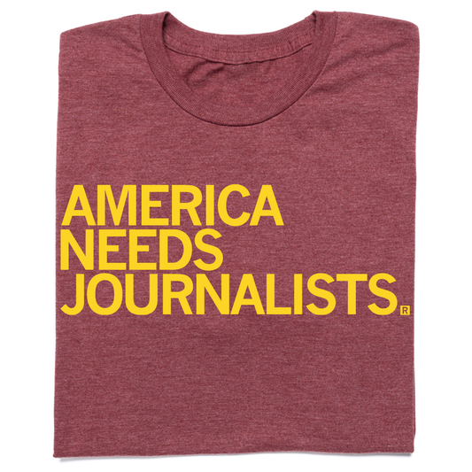 Heather burgundy t-shirt with the yellow text AMERICA NEEDS JOURNALISTS.