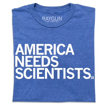 Blue t-shirt printed in the USA with the text AMERICA NEEDS SCIENTISTS in white capital letters.