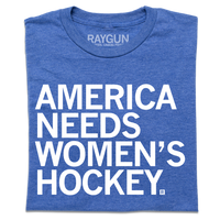 A folded heather royal blue t-shirt with left-aligned white ink text that reads "America Needs Women's Hockey"