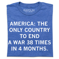 A folded heather blue t-shirt with centered white text that says, "America: The Only Country To End A Ware 38 Times In 4 Months."