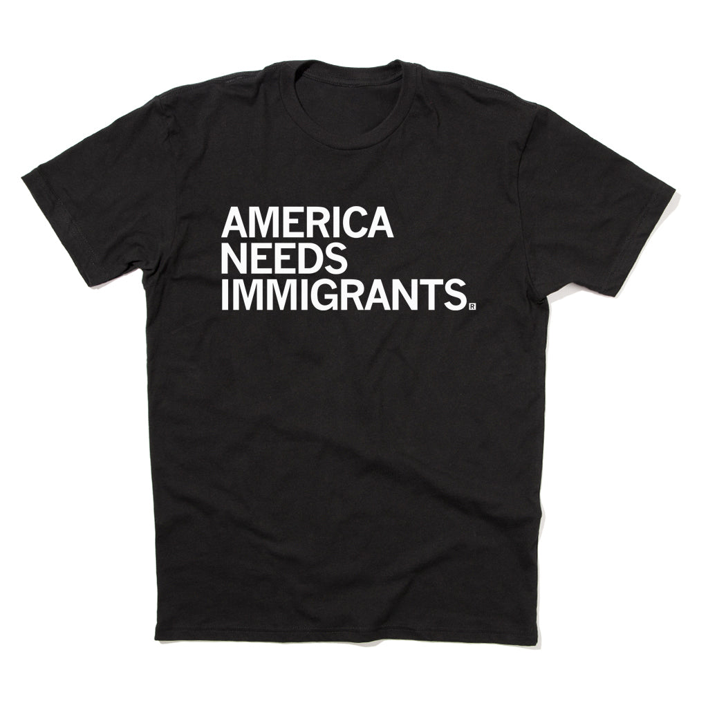 A sweatshop-free black t-shirt with the white text AMERICA NEEDS IMMIGRANTS printed on the chest.