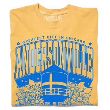 Folded heather mellow yellow t-shirt with bright blue print. Text from top-to-bottom reads "GREATEST CITY IN CHICAGO. ANDERSONVILLE. CHICAGO. SWEDE SOMMAR CHILD." There's an illustration of the Andersonville Swedish flag water tower in the center, surrounded by flowers.