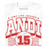 White Andi Jackson T-shirt with a red graphic featuring a volleyball, a net, the number 15, the text JUMP LIKE JACKSON, and the name ANDI in large varsity-style letters.