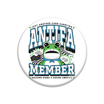 A round ANTIFA button featuring a cartoon frog wearing a blue bandana, with the text ANTIFA MEMBER and small signs that read FROG AROUND & FIND OUT and WHO LET THE FROGS OUT?.
