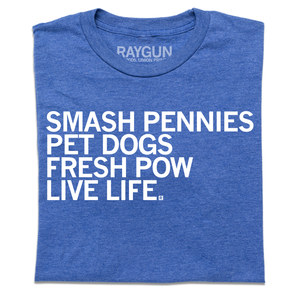 A folded heather royal blue t-shirt with left-aligned white ink text that reads "Smash pennies, pet dogs, fresh pow, live life"