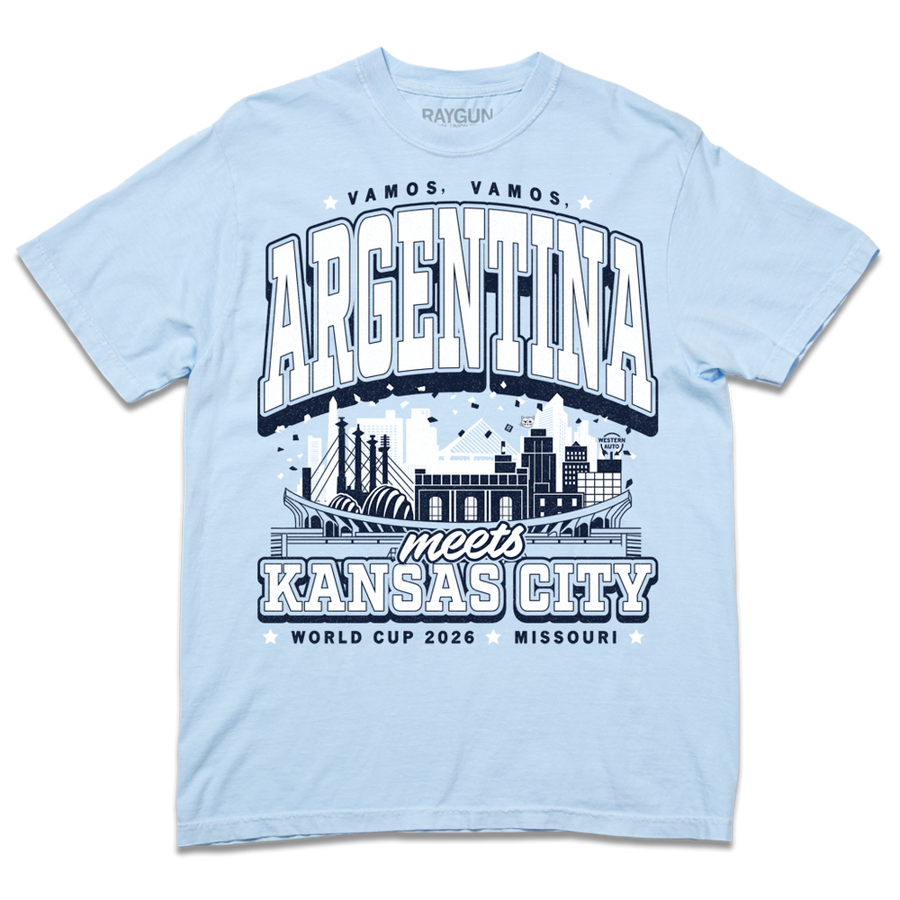 A hydrangea heavyweight t-shirt with navy and white ink. From the top to the bottom the text reads "Vamos, Vamos, Argentina meets Kansas City. World Cup 2026, Missouri." In the center is an illustration depicting notable buildings from Argentina and Kansas City mixed together.