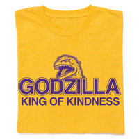 A folded heather gold t-shirt with purple ink that says, "Godzilla King of Kindness" with Godzilla's head emerging above the text.