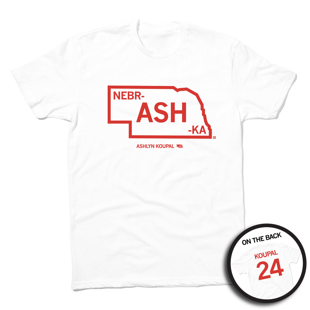 Short sleeve white t-shirt with red ink print outlining Nebraska. Text inside the state says, "NEBR-ASH-KA" with "ASHLYN KOUPAL printed in smaller text below. The back is styled like a jersey with "KOUPAL" printed over the number 24.