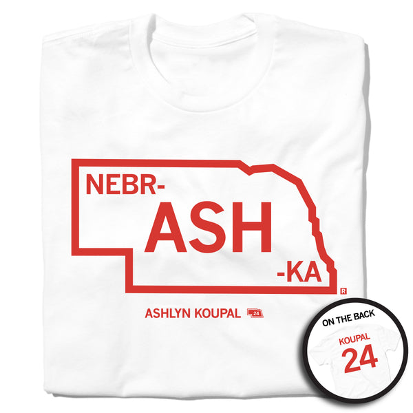 A folded white t-shirt with red ink print outlining Nebraska. Text inside the state says, 