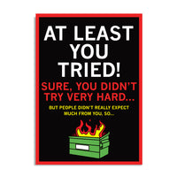 Black postcard with white, red, and gold text that says "At Least You Tried! Sure, you didn't try very hard... But people didn't really expect much from you, so..." over a dumpster fire
