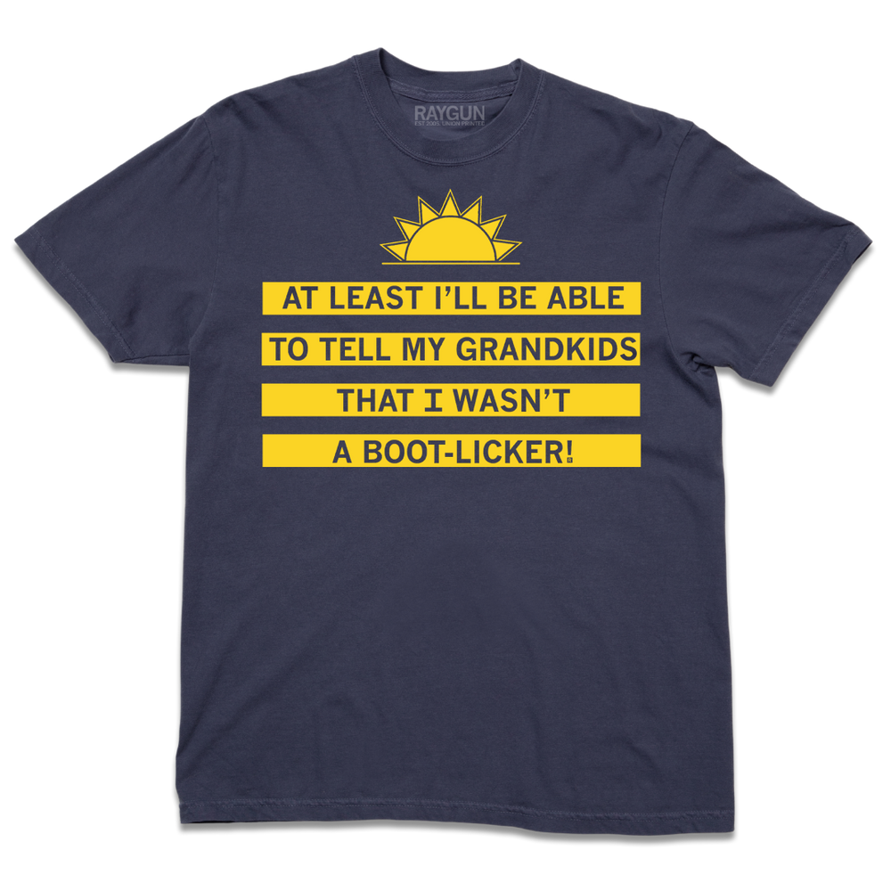 A short-sleeve navy t-shirt with a yellow ink depiction of a sunrise near the top and text below that reads "At least I'll be able to tell my grandkids that I wasn't a boot-licker!"