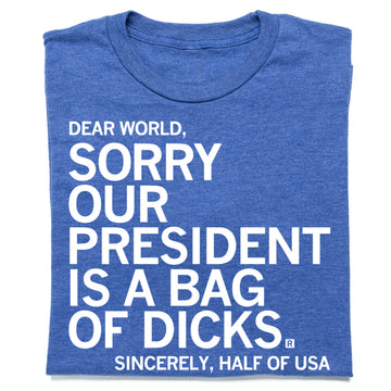 A folded heather royal blue t-shirt with white text that reads "Dear World, sorry our president is a bag of dicks. Sincerely, half of USA."