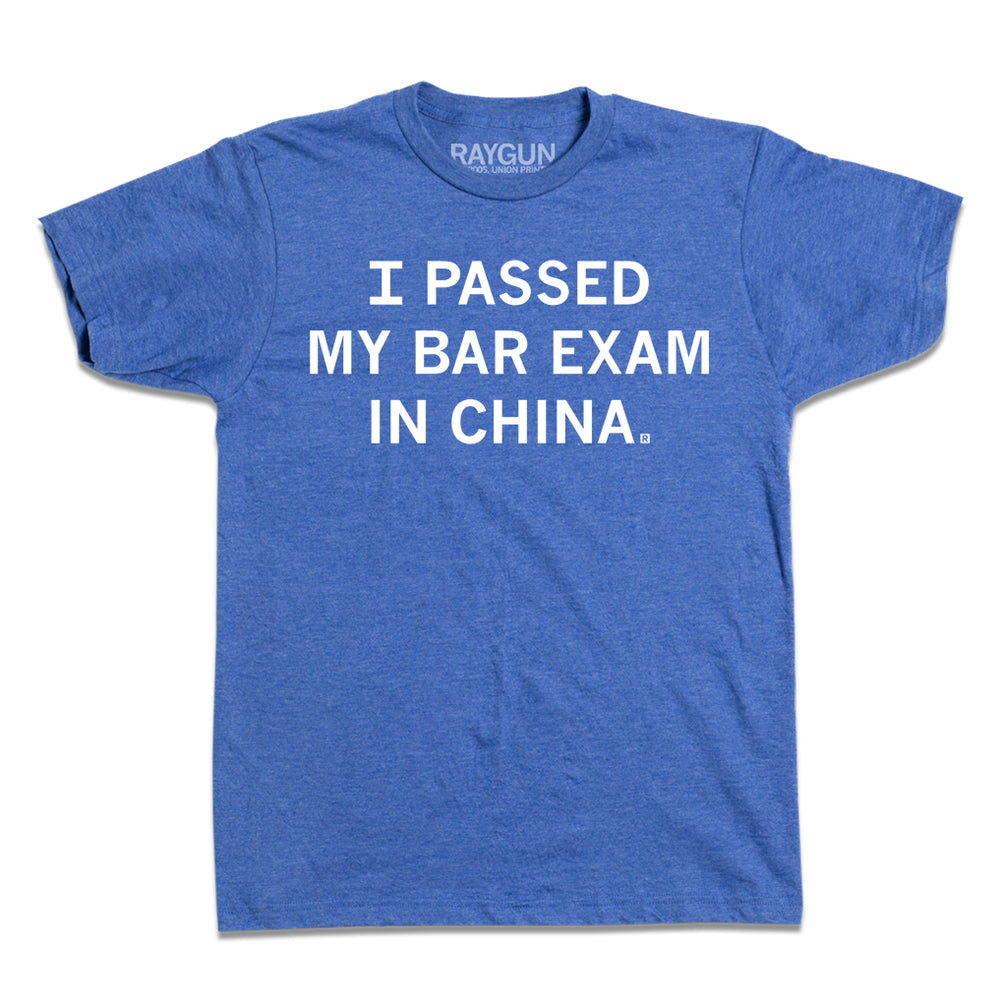 A short-sleeve heather blue t-shirt with white text that reads "I passed my bar exam in China." in all caps.