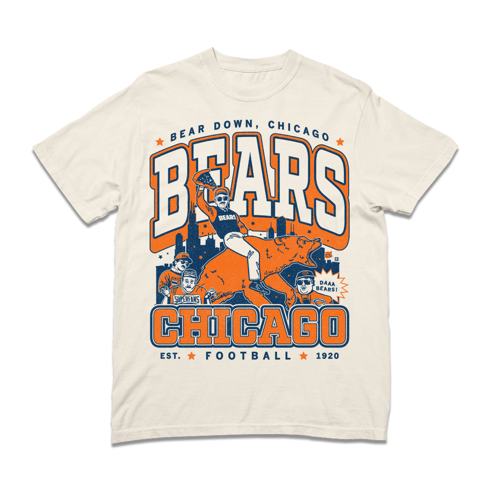 A ivory heavyweight t-shirt with a large orange & navy text that reads "Bear down, Chicago. Bears. Chicago. Est football 1920" over a graphic of a superfan holding a slice of deep dish pizza while riding a bear.