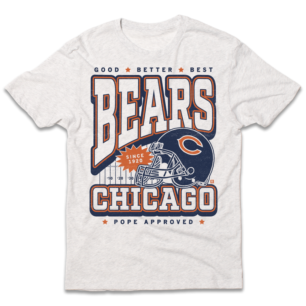 Short-sleeve heather white t-shirt with a vintage style print in orange and navy ink. Text from top to bottom reads "Good, Better, Best. Bears. Since 1920. Chicago. Pope Approved." There's a football helmet over a football field in the center.