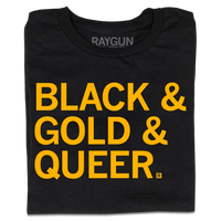 A folded black t-shirt with large, left-aligned gold text that reads "Black & Gold & Queer"