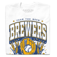 A folded white t-shirt with gold and blue ink that reads "Fear the beer. Milwaukee Brewers. American Family Field." with a baseball landing in a mitt in the center and beer hops growing on either side.