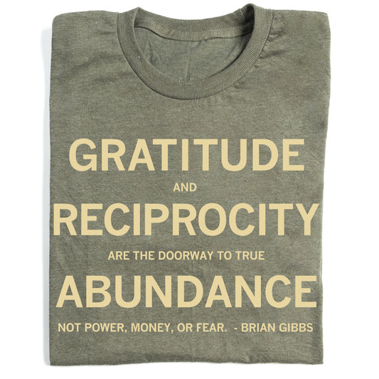 Folded heather olive shirt with cream text that says, ""Gratitude and reciprocity are the doorway to true abundance not power, money, or fear." - Brian Gibbs" in all caps.