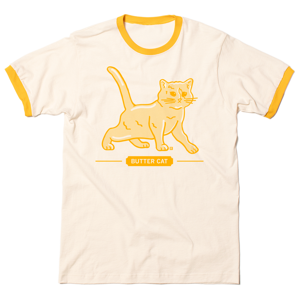 Short sleeve vintage white ringer shirt with yellow sleeve and collar accents. Gold ink printed with a gradient depicts a cat made of butter, spoofing the butter cow. Text below says "BUTTER CAT."