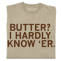 A folded khaki t-shirt with centered brown ink text that says, "Butter? I hardly know 'er" in all caps.