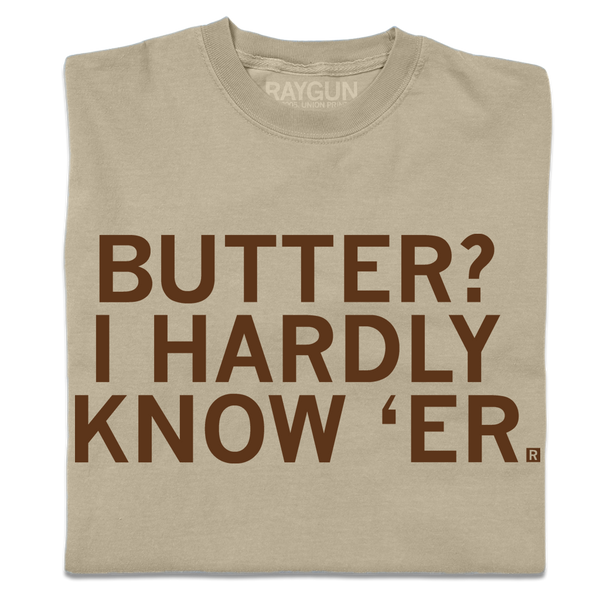 A folded khaki t-shirt with centered brown ink text that says, 