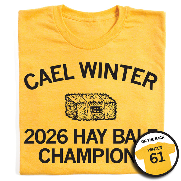 Folded heather yellow t-shirt with a black print image of a hay bale with an outline of Iowa on it and number 61 in the center. Curved text at the top says, 