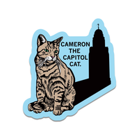 A die-cut sticker of a cat whose shadow is the Nebraska Capitol Building and black text in the center that reads "Cameron the Capitol Cat"