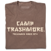 A folded brown heavyweight t-shirt with off-white ink that says, "Camp Trashmore. Treasured since 1974." printed in a font reminiscent of old summer camps.