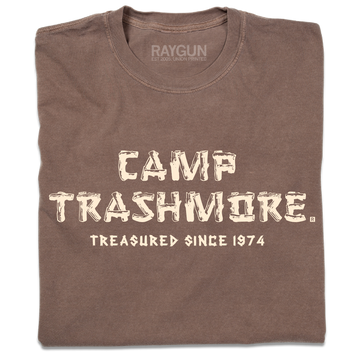 A folded brown heavyweight t-shirt with off-white ink that says, "Camp Trashmore. Treasured since 1974." printed in a font reminiscent of old summer camps.