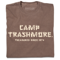 A folded brown heavyweight t-shirt with off-white ink that says, "Camp Trashmore. Treasured since 1974." printed in a font reminiscent of old summer camps.