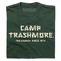 A folded forest green t-shirt with off-white ink that says, "Camp Trashmore. Treasured since 1974." printed in a font reminiscent of old summer camps.