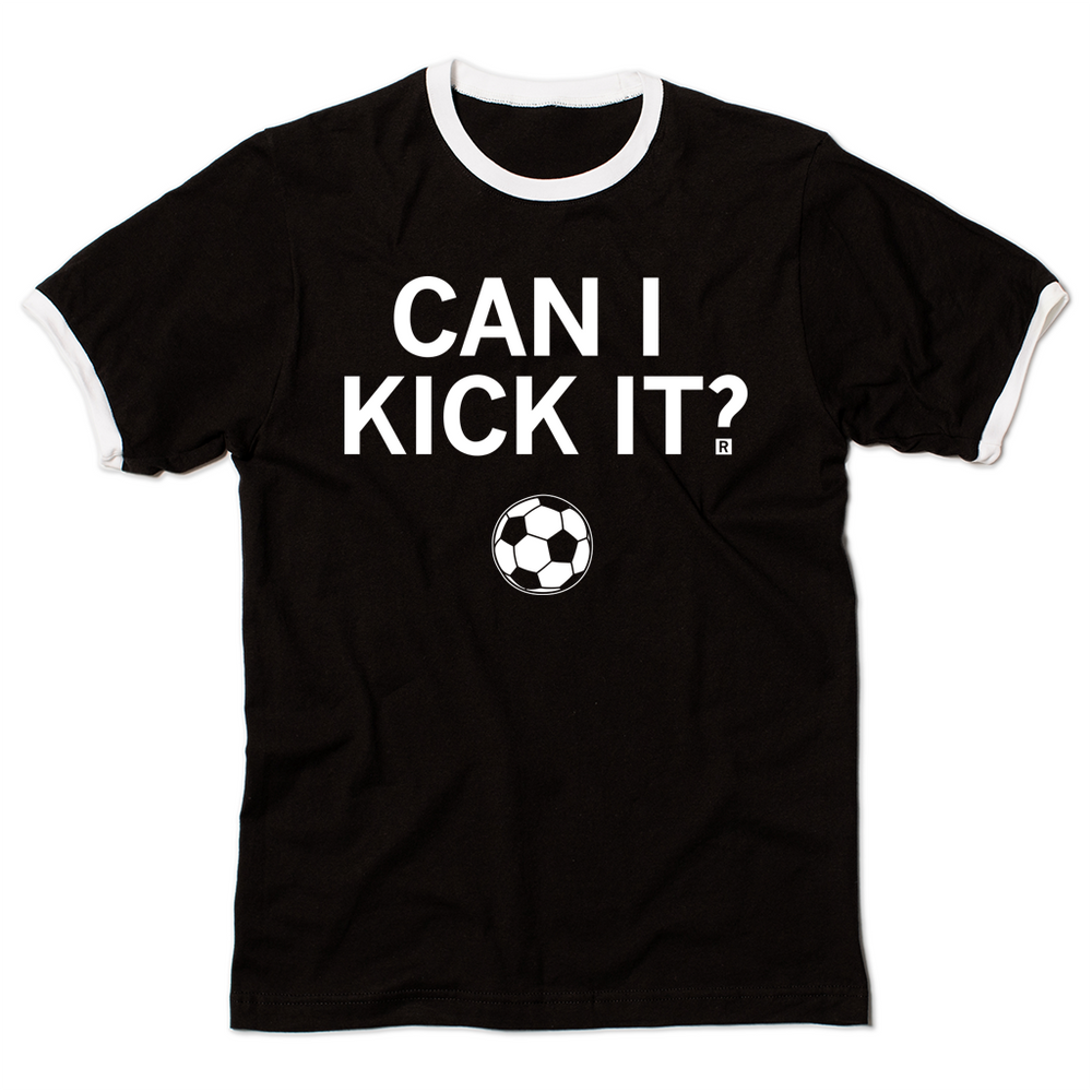 A black ringer t-shirt with a white neckline and sleeves. Centered white ink text reads can I kick it?" above an illustration of a soccer ball.
