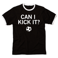 A black ringer t-shirt with a white neckline and sleeves. Centered white ink text reads can I kick it?" above an illustration of a soccer ball.