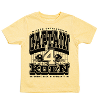 Pastel yellow youht t-shirt with black ink that reads "Koen Entrigner. Captain Koen. Defensive Back. Ypsilanti, MI" over an illustration of a football field with a large number 4 in the center and a football helmet to either side.