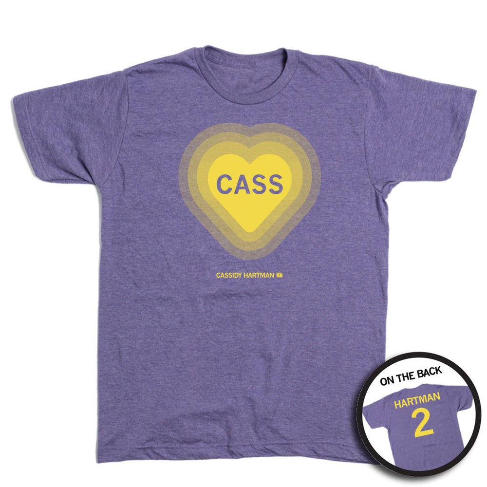 A heather purple t-shirt with gold ink. The front has a gold heart with the name Cass in the center and "Cassidy Hartman" at the bottom. The back reads "Hartman 2"