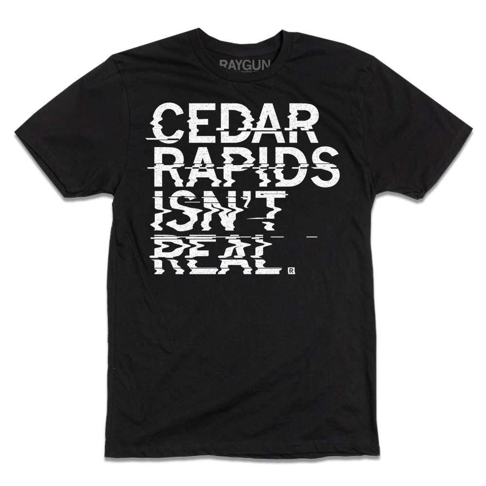 Black t-shirt with left-aligned white ink text printed in a distorted style that reads "Cedar Rapids Isn't Real"
