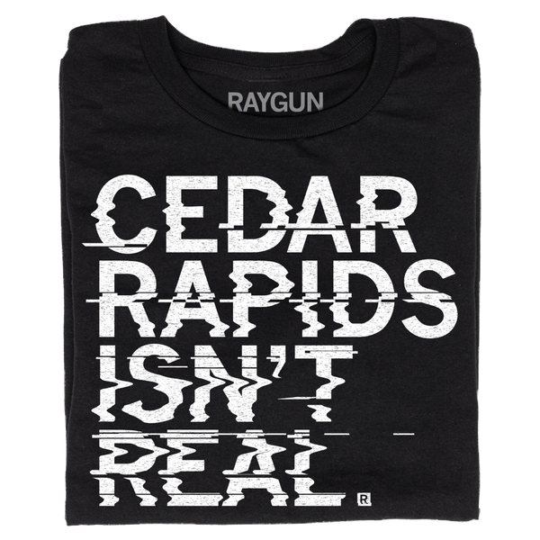 A folded black t-shirt with left-aligned white ink text printed in a distorted style that reads 