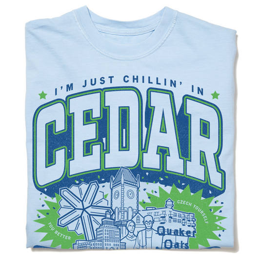 Light blue, ringspun cotton t-shirt with a graphic that reads IM JUST CHILLIN IN CEDAR above a windmill, clock tower, and Quaker Oats logo.