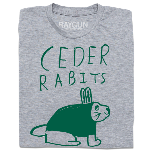 A folded heather grey t-shirt with kelly green ink that says, "Ceder Rabits" above an illustration of a rabbit. This shirt was designed by a kid taking part in a contest at our Cedar Rapids store.