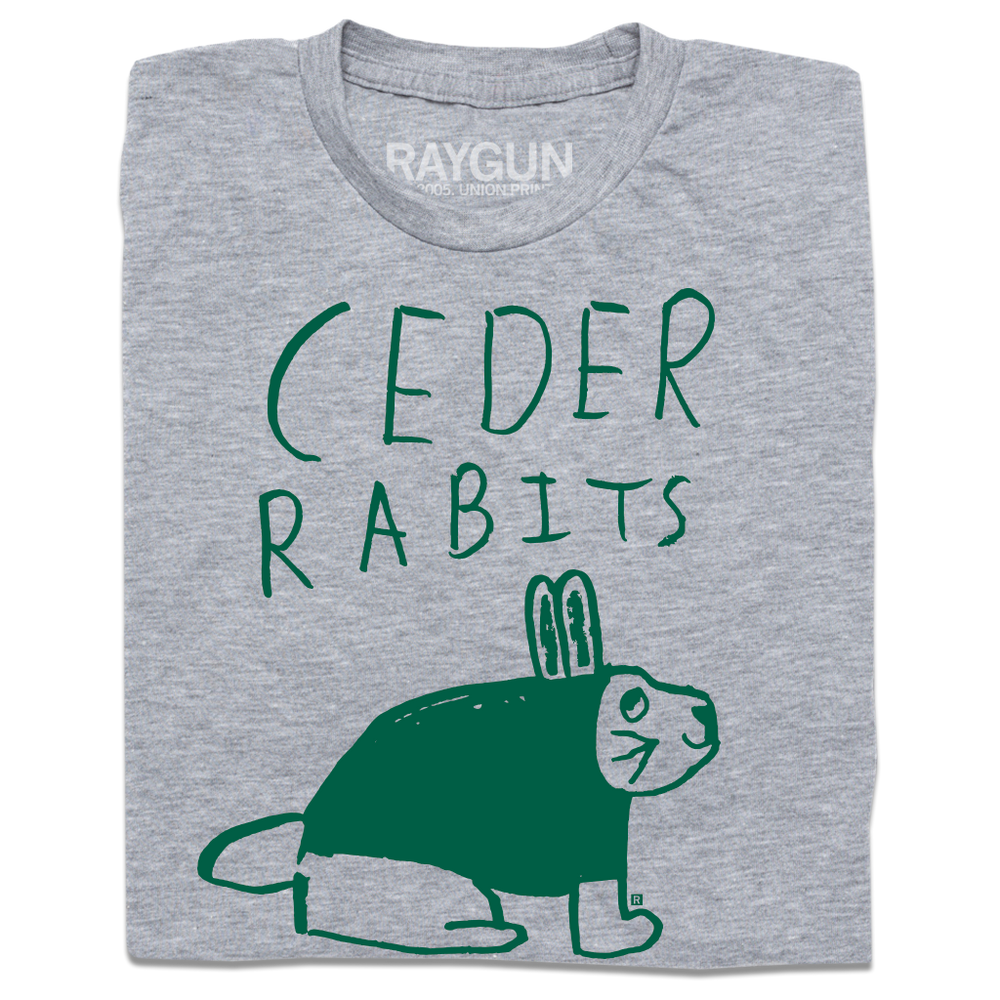 A folded heather grey t-shirt with kelly green ink that says, "Ceder Rabits" above an illustration of a rabbit. This shirt was designed by a kid taking part in a contest at our Cedar Rapids store.