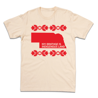 Short sleeve cream t-shirt with bright red ink print of Nebraska with cream text over the bottom of the state that says, "NYI BRATHGE IS INDIGENOUS LAND". 