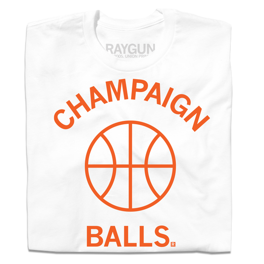 A folded white t-shirt with orange ink. There's curved text at the top that reads "Champaign," a outline of a basketball in the center and text at the bottom that says, "Balls."