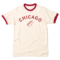 A folded ivory and red ringer shirt with  curved red ink text that says, "Chicago" over an illustration of a Chicago style hot dog.