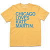 Comfort Colors short-sleeve heavyweight mustard t-shirt with left-aligned bright blue text that says, "Chicago Loves Kate Martin" in all caps.