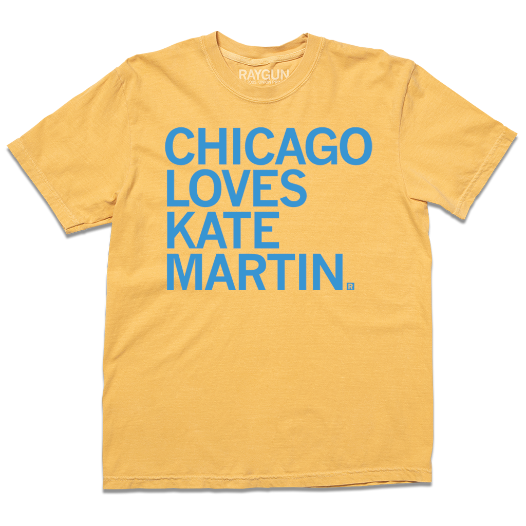 Comfort Colors short-sleeve heavyweight mustard t-shirt with left-aligned bright blue text that says, "Chicago Loves Kate Martin" in all caps.