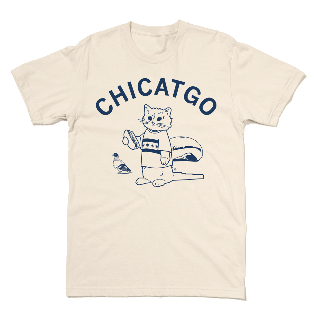 A cream colored tee with curved navy ink that reads "Chicatgo" over an illustration of RAYGUN's cat mascot wearing a Chicago flag t-shirt while holding a hotdog. The Bean is behind him and there's a pigeon beside him.
